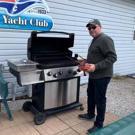 A member grilling hot dogs on the barbecue by the clubhouse
