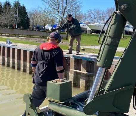 A crew member at the barge controls beside the seawall