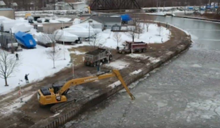 An excavator dredging along the members’ slips in early spring