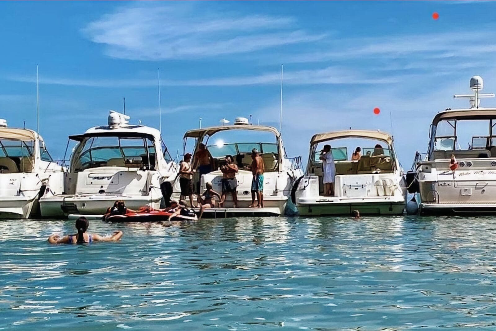 Boats rafted up with swimmers in clear water